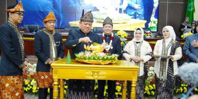 Pj. Bupati Kabupaten Musi Banyuasin, Sandi Fahlepi, memotong tumpeng pada perayaan Hari Ulang Tahun (HUT) Kabupaten Musi Banyuasin (Muba) ke 68, tergambar dalam Sidang Paripurna Dewan Perwakilan Rakyat Daerah (DPRD) yang berlangsung pada hari Sabtu pagi, tanggal 28 September 2024. (BekisarMedia.id/Eka Sahputra)