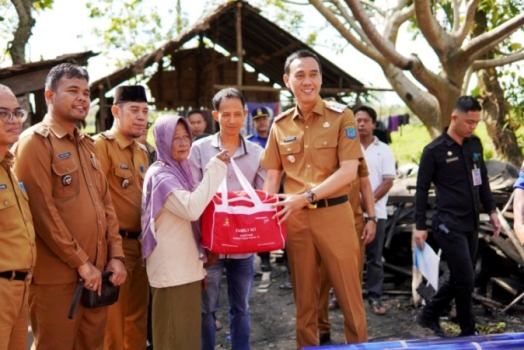 Bupati Kabupaten Ogan Komering Ilir, H. Muchendi, menyerahkan bantuan kepada Bandaria, seorang ibu yang tinggal bersama empat anaknya di Desa Celikah, Kecamatan Kayuagung, pada hari Senin, tanggal 14 April 2025. (BEKISARMEDIA.ID/SIKUMBANG)